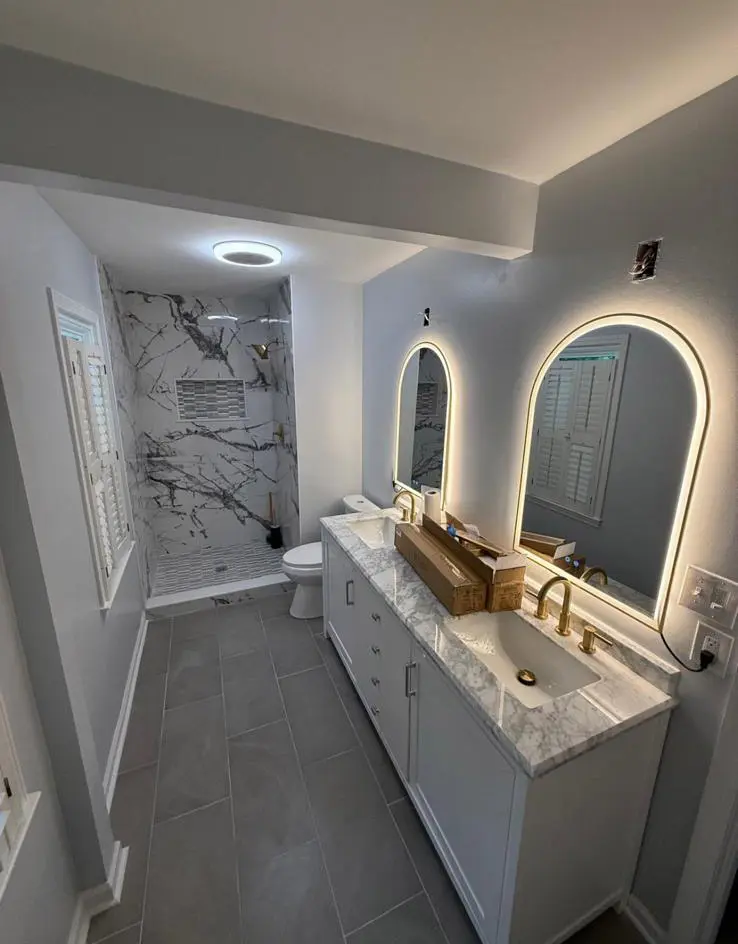 Completed gray bathroom remodel with custom vanity and lighted mirrors